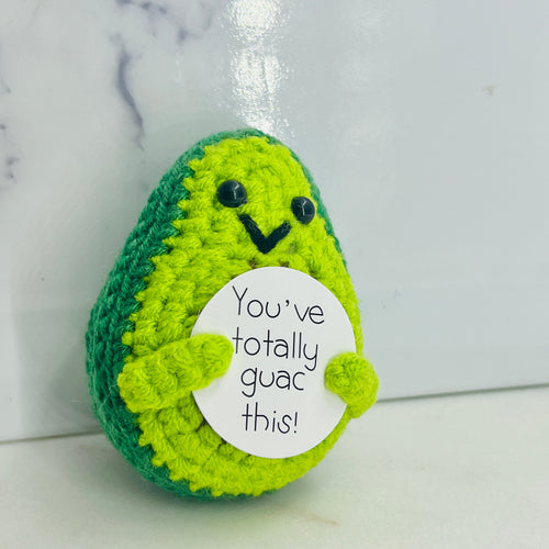 Crocheted avocado with a face and a tag saying 'You've totally guac this!' on a marble background.