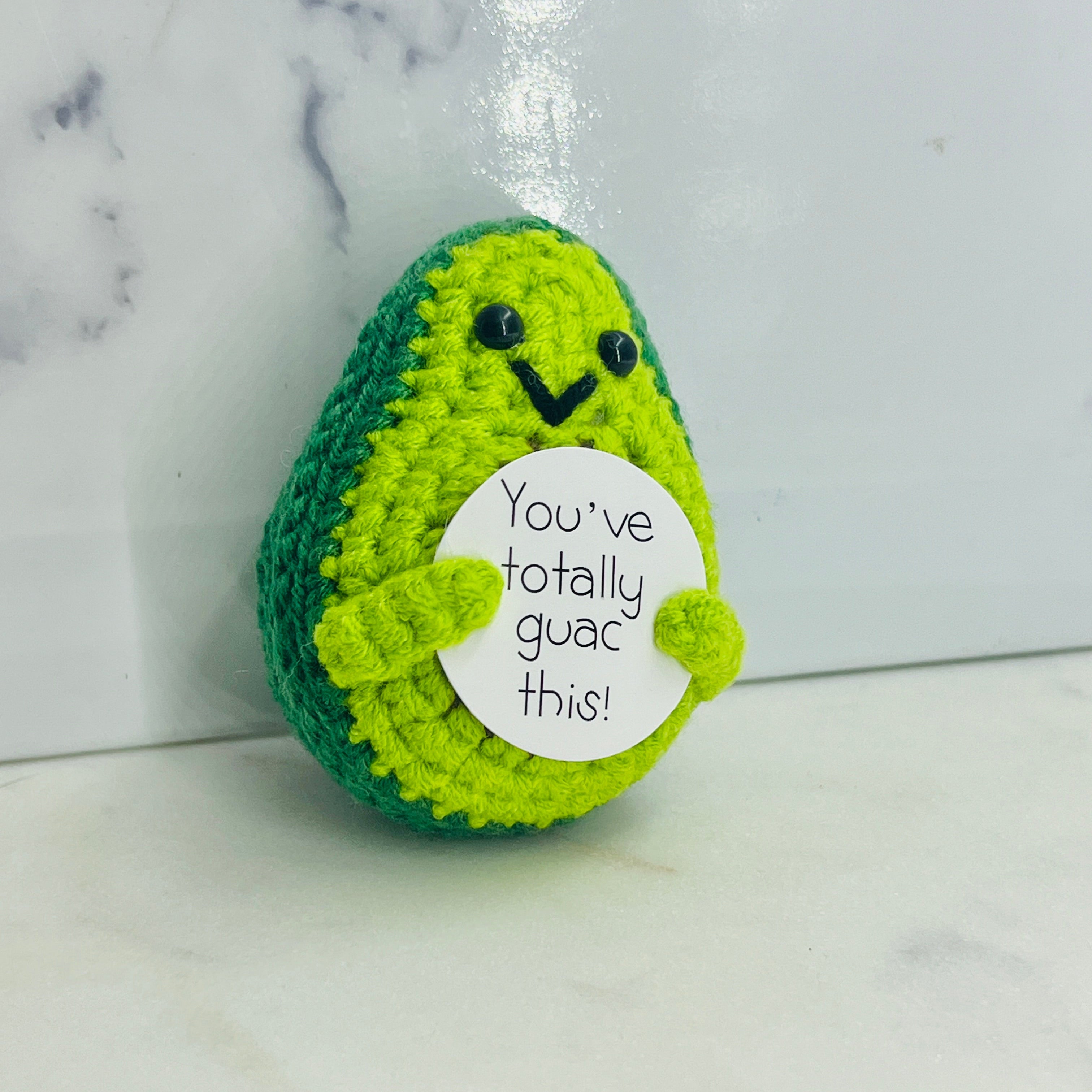Crocheted avocado plush toy with a humorous message 
